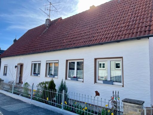 Ein gemütliches, helles Haus mit roten Ziegeldach und gepflegtem Vorgarten.